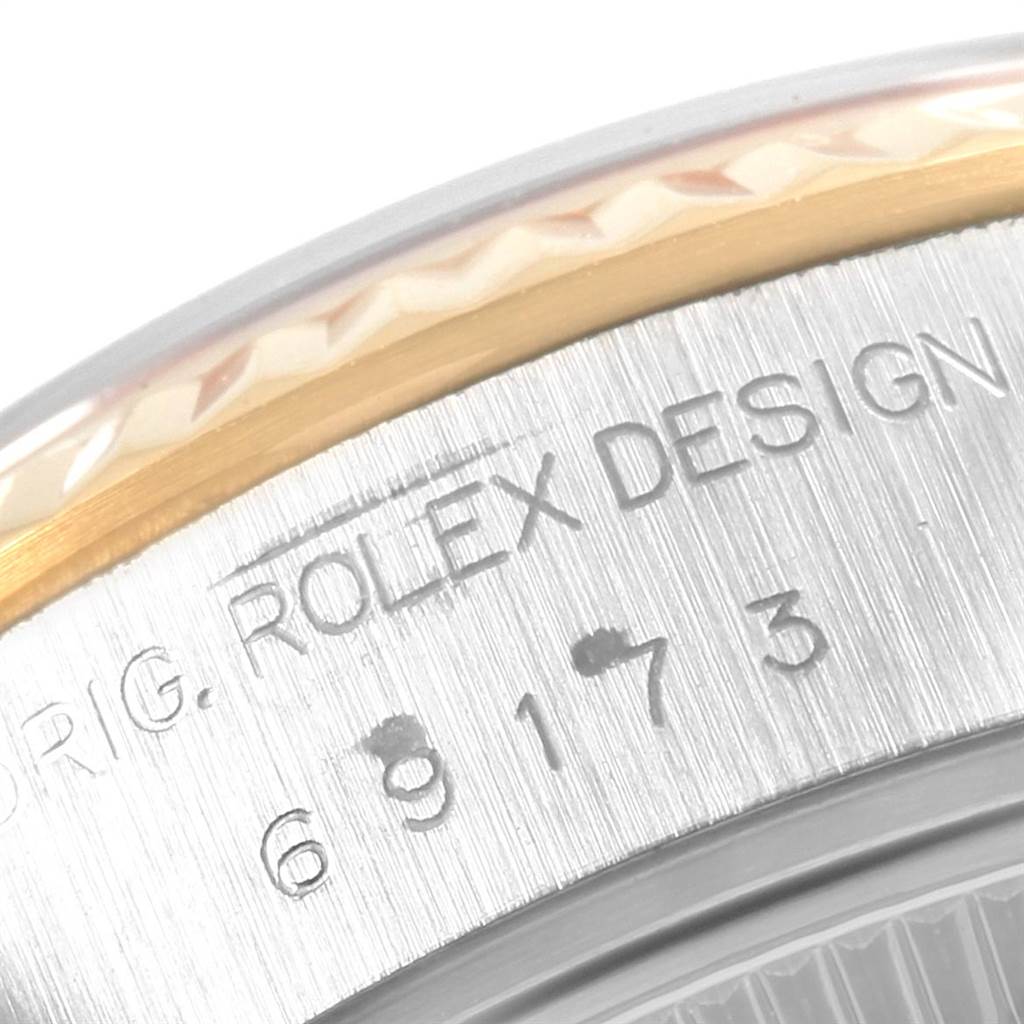 The image shows a close-up of the bezel and case side of a Rolex Datejust 69173 Women's Stainless Steel White Dial 69173 Women's Stainless Steel White Dial watch, including part of the serial number and "Rolex Design" engraving.