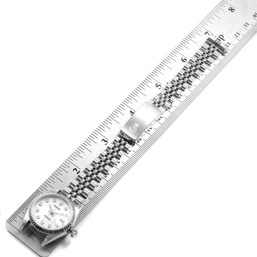 The image shows the Rolex Datejust 79174 Women
s Stainless Steel Silver Dial 79174 Women
s Stainless Steel Silver Dial watch laying flat on a ruler, highlighting the face, bracelet, and clasp.