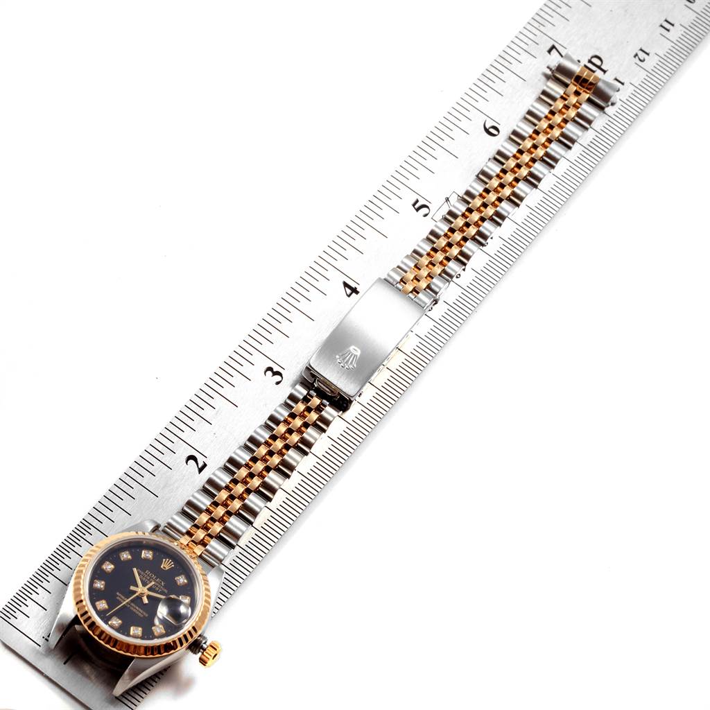 The Rolex Datejust 79173 Women
s Steel and Gold (two tone) Black Dial 79173 Women
s Steel and Gold (two tone) Black Dial watch is shown from the top, with its full bracelet displayed along a ruler for measurement.