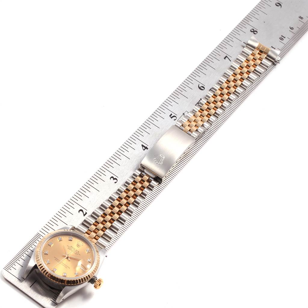 A Rolex Datejust 68273 Women's Steel and Gold (two tone) Champagne Dial 68273 Women's Steel and Gold (two tone) Champagne Dial watch is shown face-up, alongside a ruler, highlighting its gold bezel, dial, and two-tone jubilee bracelet.