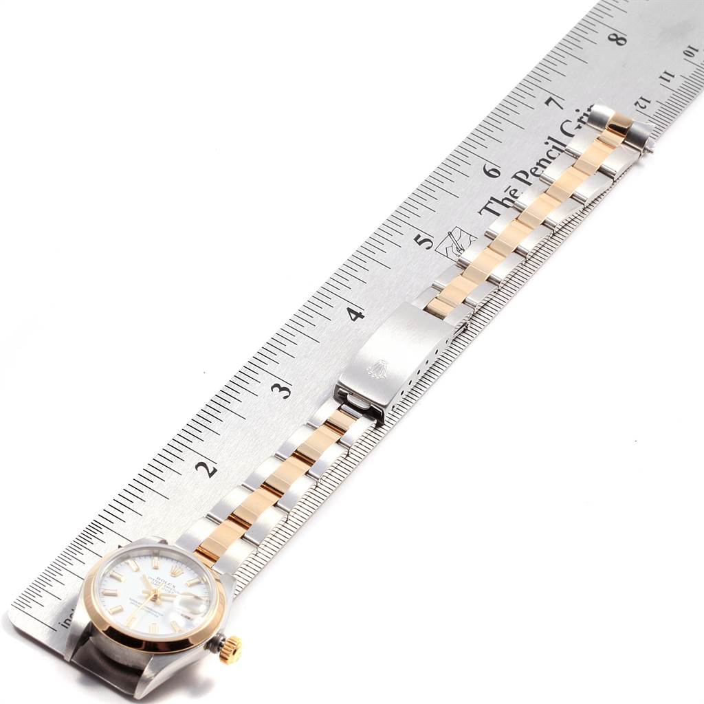 The Rolex Datejust 79163 Women's Steel and Gold (two tone) White Dial 79163 Women's Steel and Gold (two tone) White Dial watch is shown in a flat-lay angle with its full bracelet and clasp alongside a ruler.