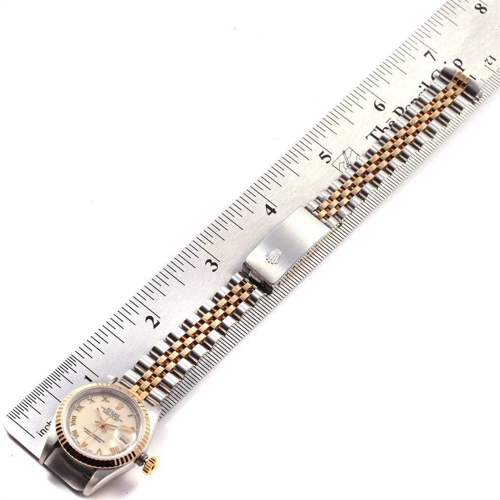 The image shows a Rolex Datejust 69173 Women
s Stainless Steel Beige Dial 69173 Women
s Stainless Steel Beige Dial watch laid flat against a ruler, displaying its face, crown, and metal bracelet with clasp.