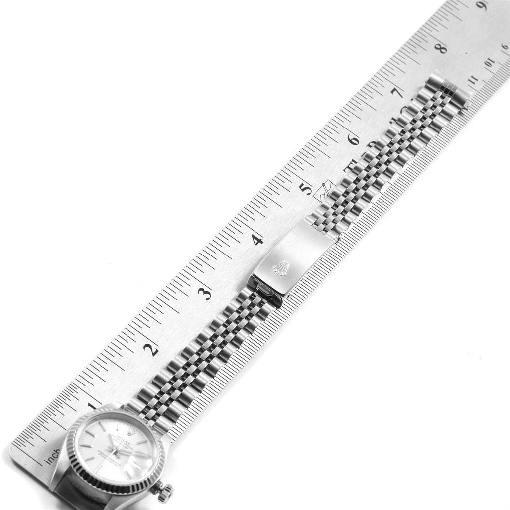 This image shows a Rolex Datejust 79174 Women
s Stainless Steel Silver Dial 79174 Women
s Stainless Steel Silver Dial watch laid flat with its Jubilee bracelet alongside a ruler for measurement.