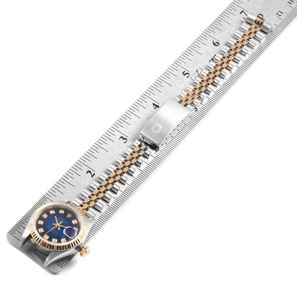 The image shows the Rolex Datejust 79173 Women's Steel and Gold (two tone) Blue Dial 79173 Women's Steel and Gold (two tone) Blue Dial watch positioned alongside a ruler, focusing on its face and bracelet.