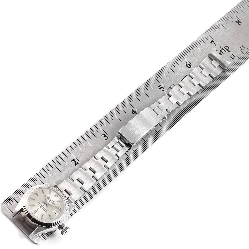 The Rolex Datejust 69174 Women's Stainless Steel Silver Dial 69174 Women's Stainless Steel Silver Dial watch is shown lying flat next to a ruler, displaying its face, bracelet, and clasp.