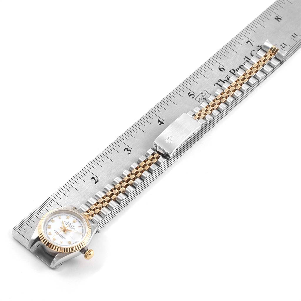 The image shows a Rolex Datejust 69173 Women's Stainless Steel White Dial 69173 Women's Stainless Steel White Dial watch with its face, fluted bezel, and Jubilee bracelet placed beside a ruler.