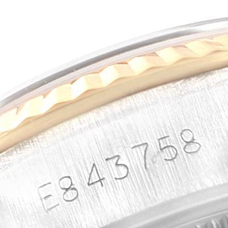 This close-up image of a Rolex Datejust 69173 Women's Stainless Steel Black Dial 69173 Women's Stainless Steel Black Dial watch shows part of the fluted bezel and serial number engraving on the case.