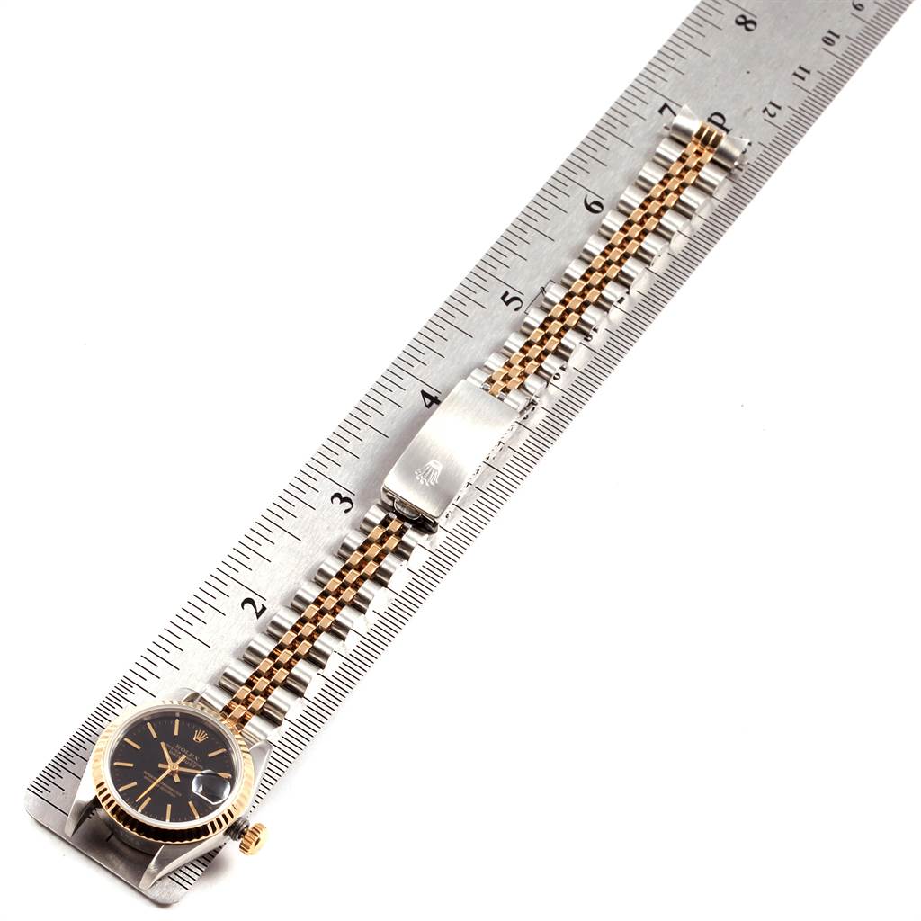 The Rolex Datejust 69173 Women's Stainless Steel Black Dial 69173 Women's Stainless Steel Black Dial watch is shown from above with its bracelet extended aligned next to a measuring ruler.