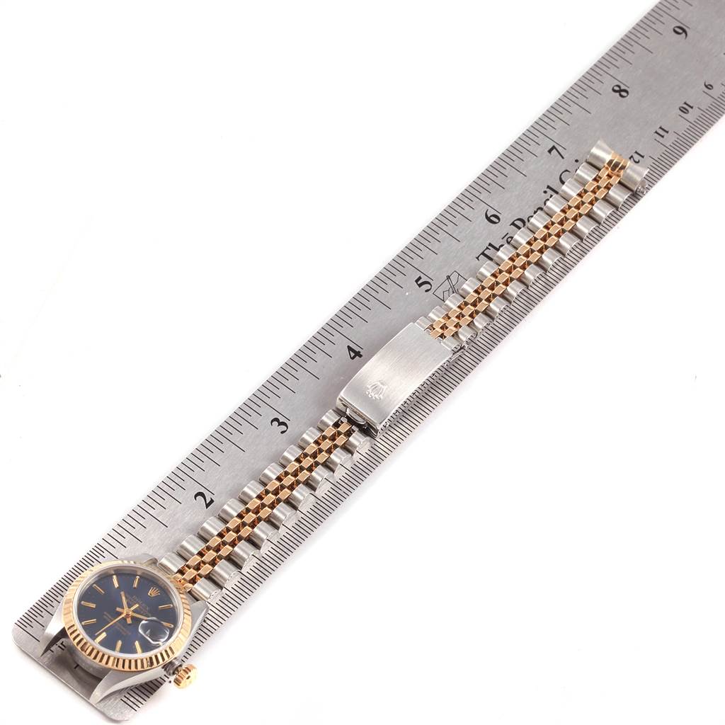 The Rolex Datejust 69173 Women's Stainless Steel Blue Dial 69173 Women's Stainless Steel Blue Dial watch is displayed from a top-down angle, showing the face, fluted bezel, two-tone bracelet, and clasp alongside a ruler.