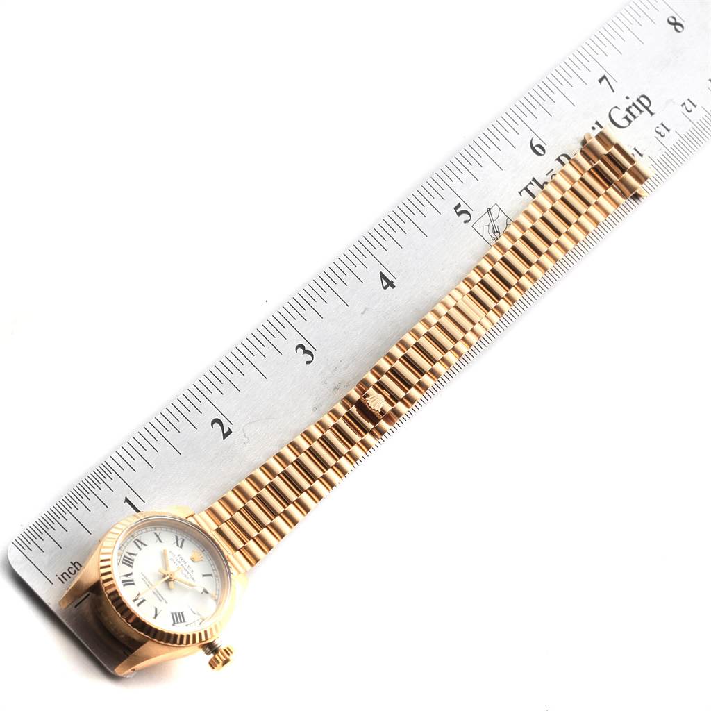 The Rolex Datejust 6917 Women's Yellow Gold White Dial 6917 Women's Yellow Gold White Dial watch is shown from a top-down angle, featuring the full face, bezel, and bracelet alongside a ruler.