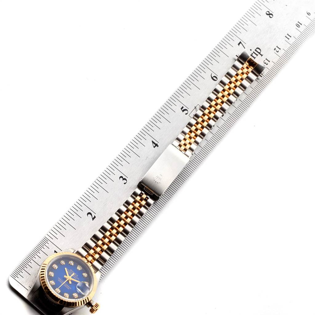 The image shows a Rolex Datejust 69173 Women's Steel and Gold (two tone) Blue Dial 69173 Women's Steel and Gold (two tone) Blue Dial watch with a blue dial and jubilee bracelet next to a metal ruler measuring its length.