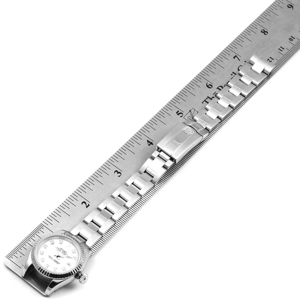 The image shows a top-down view of a Rolex Datejust 179174 Women
s Stainless Steel White Dial 179174 Women
s Stainless Steel White Dial watch placed beside a ruler for measurement, highlighting its dial and bracelet.