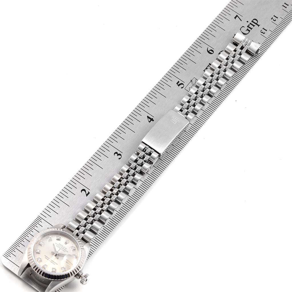 The image shows the Rolex Datejust 69174 Women
s Stainless Steel Silver Dial 69174 Women
s Stainless Steel Silver Dial watch lying flat with its face, bezel, and Jubilee bracelet visible alongside a ruler.