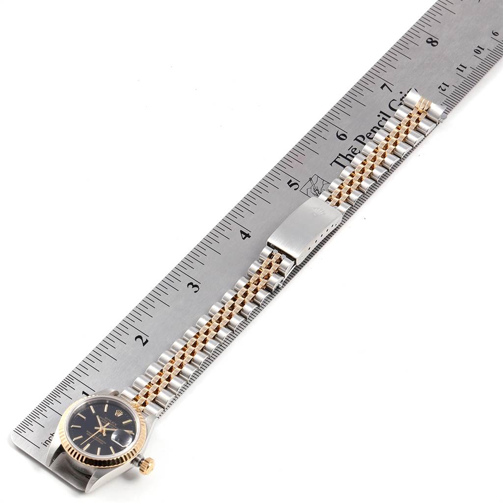 The image shows a Rolex Datejust 69173 Women
s Stainless Steel Black Dial 69173 Women
s Stainless Steel Black Dial watch laid flat next to a ruler, displaying its bezel, dial, crown, and bracelet.