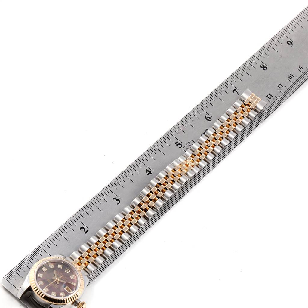 The image shows the Rolex Datejust 179173 Women's Steel and Gold (two tone) Mother of Pearl Dial 179173 Women's Steel and Gold (two tone) Mother of Pearl Dial watch laid flat next to a ruler, displaying part of its face and band.