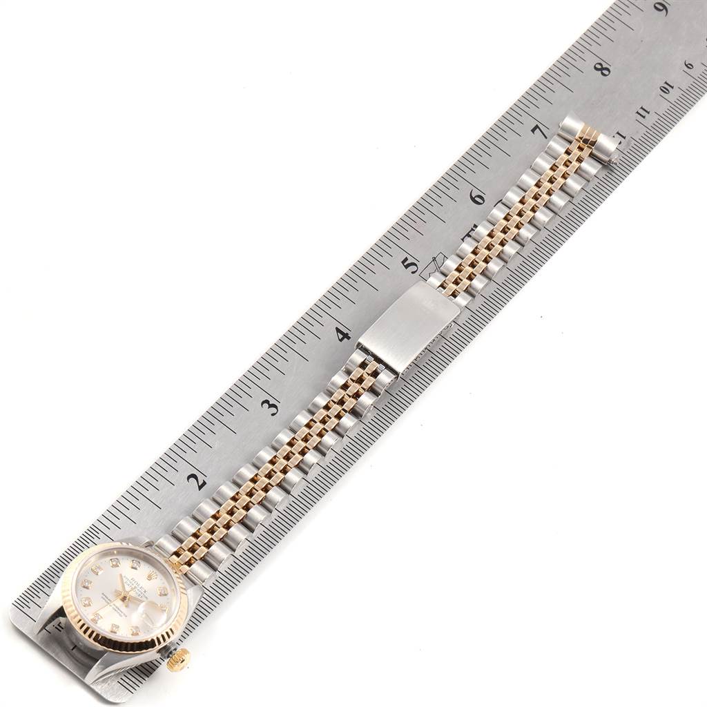 The Rolex Datejust 79173 Women's Stainless Steel Silver Dial 79173 Women's Stainless Steel Silver Dial watch is shown from a top-down angle displaying the watch face, bracelet, and clasp alongside a ruler for scale.