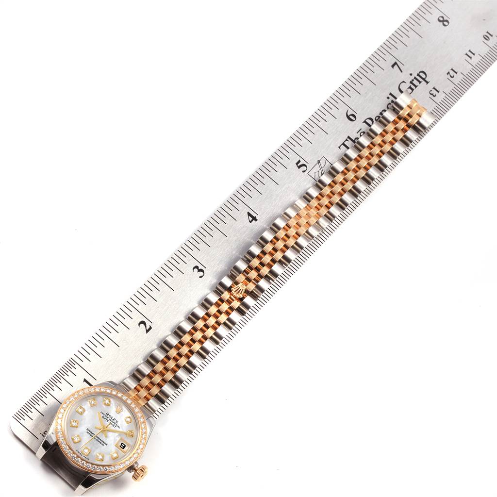 The image shows a top view of a Rolex Datejust 179383 Women's Steel and Gold (two tone) Mother of Pearl Dial 179383 Women's Steel and Gold (two tone) Mother of Pearl Dial watch with its face and two-tone bracelet positioned alongside a ruler.