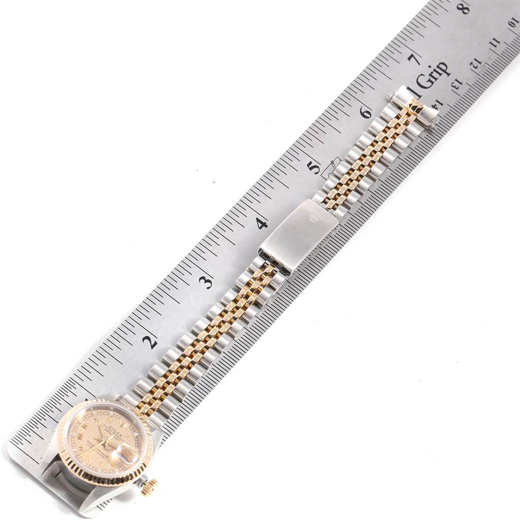 The Rolex Datejust 69173 Women's Stainless Steel Champagne Dial 69173 Women's Stainless Steel Champagne Dial watch is shown from a top view, displaying part of the face, crown, and bracelet beside a ruler.