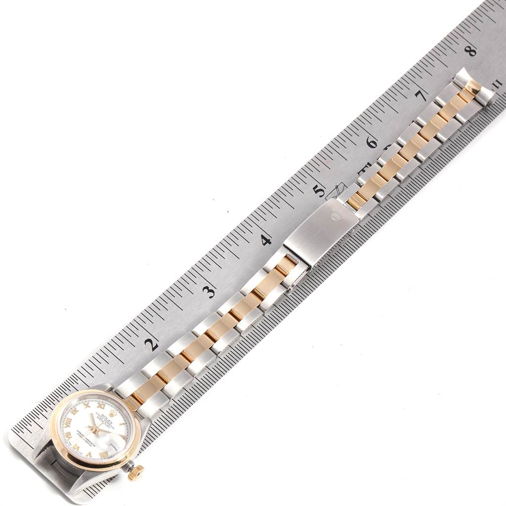 The Rolex Datejust 69163 Women's Stainless Steel White Dial 69163 Women's Stainless Steel White Dial watch is shown from a top view, displaying the face, crown, and bracelet along a ruler.