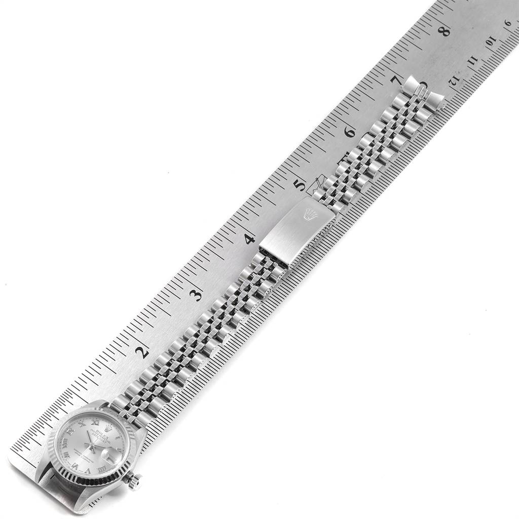 The image shows a Rolex Datejust 79174 Women
s Stainless Steel Silver Dial 79174 Women
s Stainless Steel Silver Dial watch with its bracelet and clasp laid flat and aligned with a ruler for measurement.