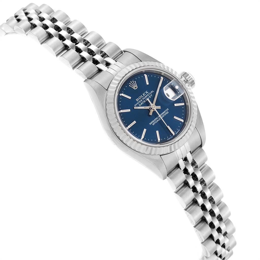The image shows a tilted side view of the Rolex Datejust 79174 Women's Stainless Steel Blue Dial 79174 Women's Stainless Steel Blue Dial watch, highlighting its blue dial, fluted bezel, and jubilee bracelet.