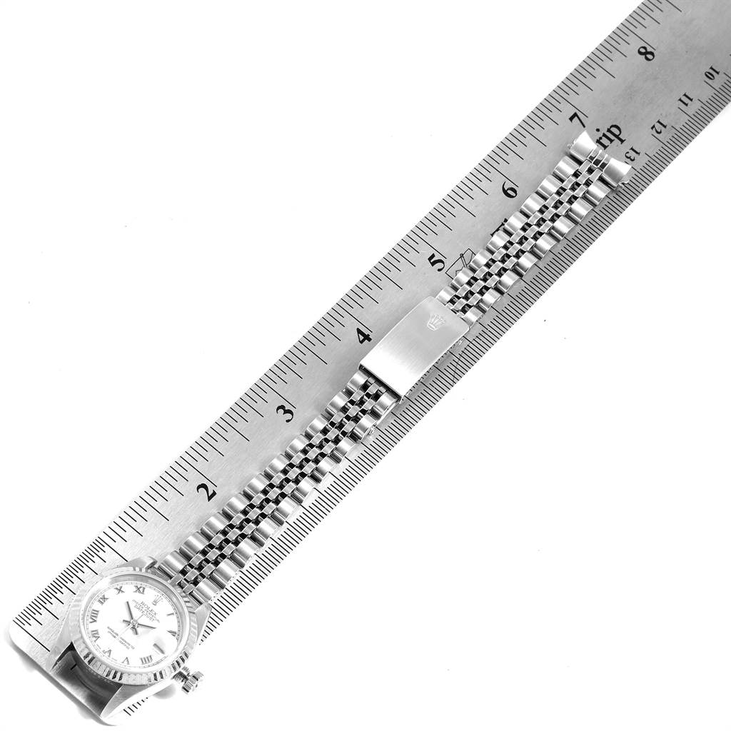 The image shows a Rolex Datejust 79174 Women's Stainless Steel White Dial 79174 Women's Stainless Steel White Dial watch layed flat under a ruler, revealing the face, case, and bracelet.