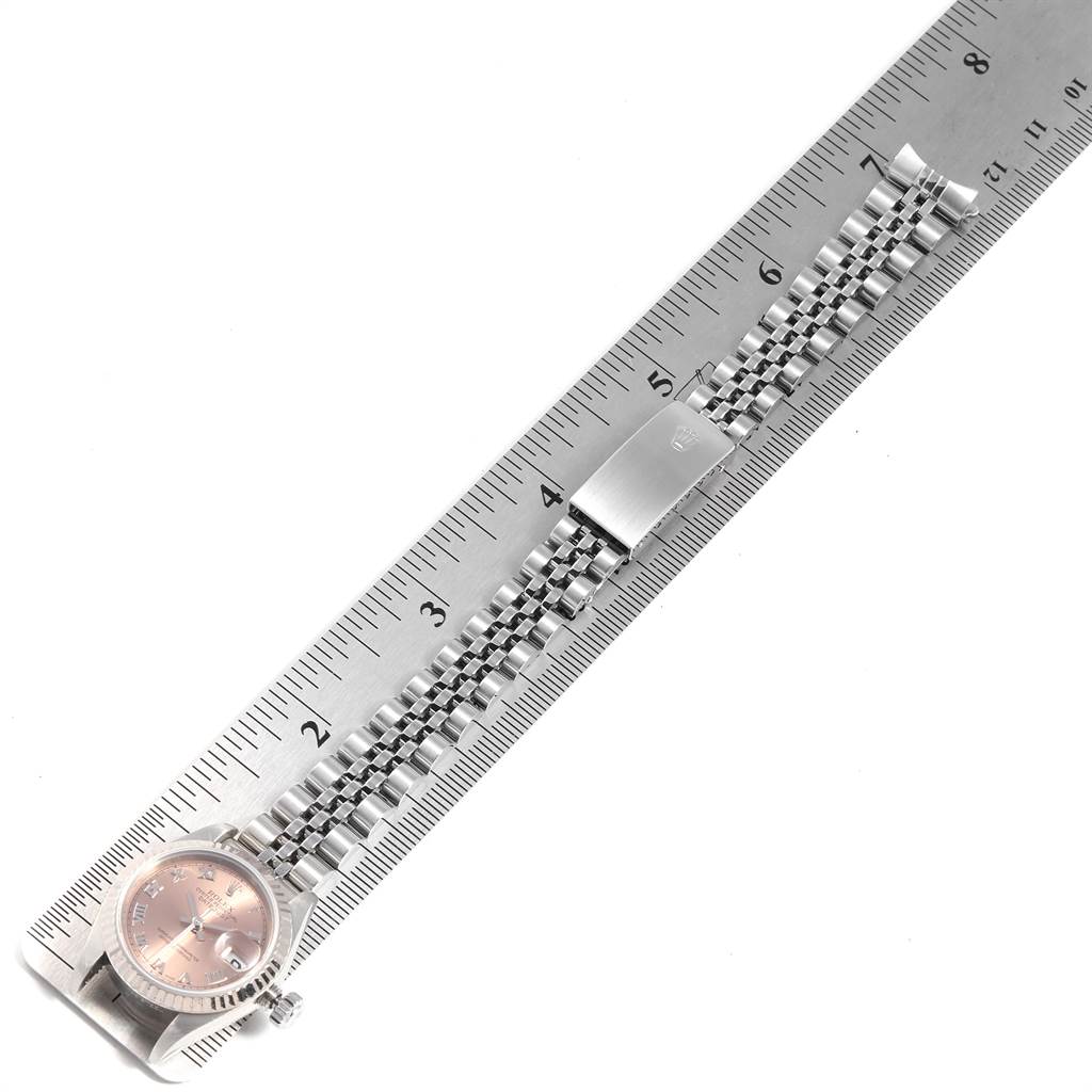 The image shows the Rolex Datejust 79174 Women's Stainless Steel Pink Dial 79174 Women's Stainless Steel Pink Dial watch lying flat against a ruler, highlighting the watch face and band.