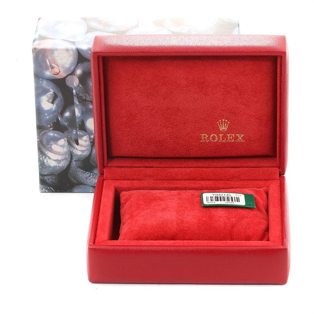 The image shows a Rolex Datejust 79173 Women
s Stainless Steel Black Dial 79173 Women
s Stainless Steel Black Dial watch box with a red interior and no watch inside, topped with a green-tagged cushion.