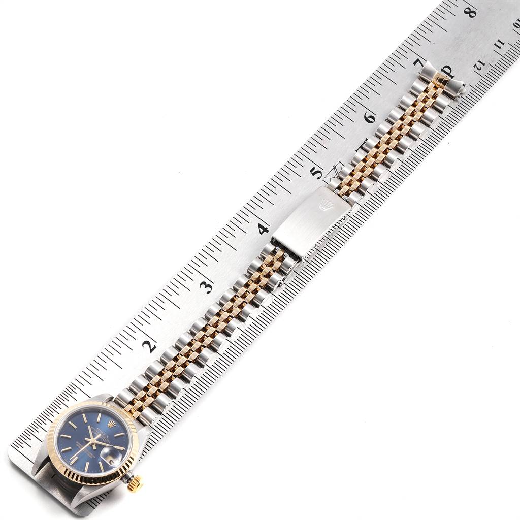 This image shows a Rolex Datejust 79173 Women
s Steel and Gold (two tone) Blue Dial 79173 Women
s Steel and Gold (two tone) Blue Dial watch laid flat alongside a ruler, displaying the face, bracelet, and clasp.
