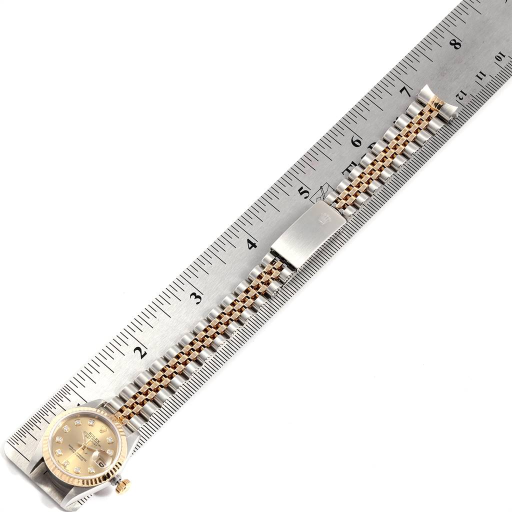 The Rolex Datejust 69173 Women's Stainless Steel Champagne Dial 69173 Women's Stainless Steel Champagne Dial watch is shown lying flat alongside a ruler, displaying its band and face with a gold dial.