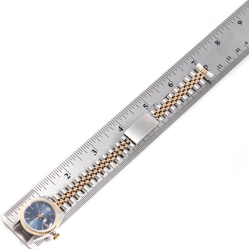 The Rolex Datejust 69173 Women's Stainless Steel Blue Dial 69173 Women's Stainless Steel Blue Dial watch is displayed face-up, alongside a metal ruler to measure the length of its band.