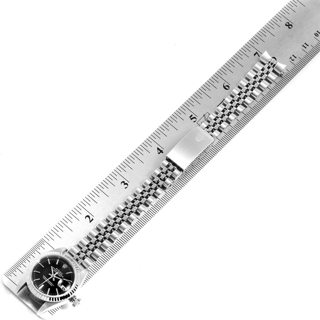The image shows a Rolex Datejust 69174 Women's Stainless Steel Black Dial 69174 Women's Stainless Steel Black Dial watch laid flat with a metallic band aligned next to a ruler for measurement.