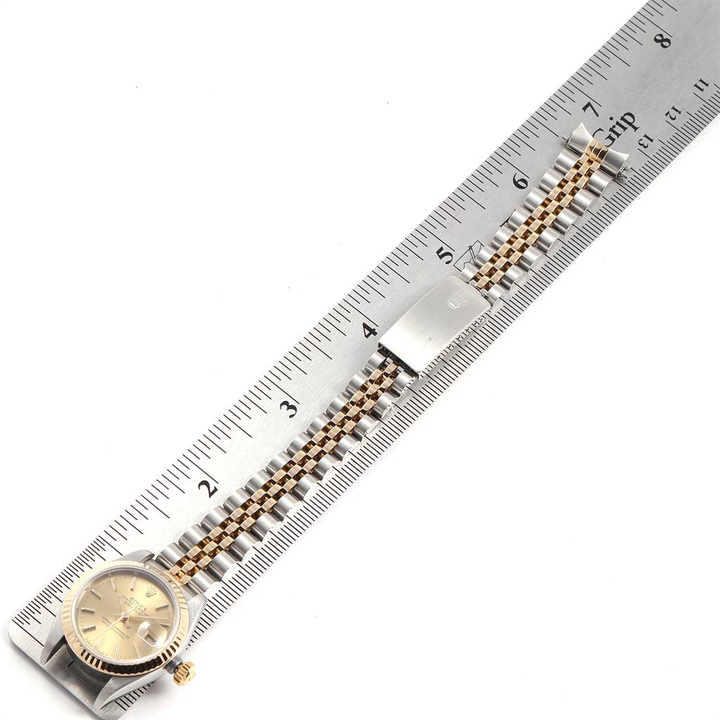 The image shows a Rolex Datejust 79173 Women
s Steel and Gold (two tone) Champagne Dial 79173 Women
s Steel and Gold (two tone) Champagne Dial watch with a gold and steel Jubilee bracelet, laid flat next to a ruler.