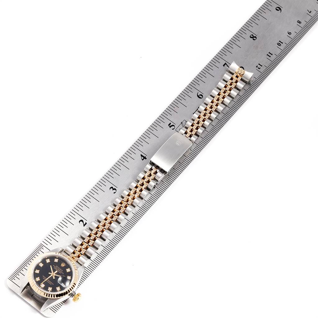 The image shows a top view of a Rolex Datejust 69173 Women
s Stainless Steel Black Dial 69173 Women
s Stainless Steel Black Dial watch placed alongside a ruler, highlighting the watch face and band.