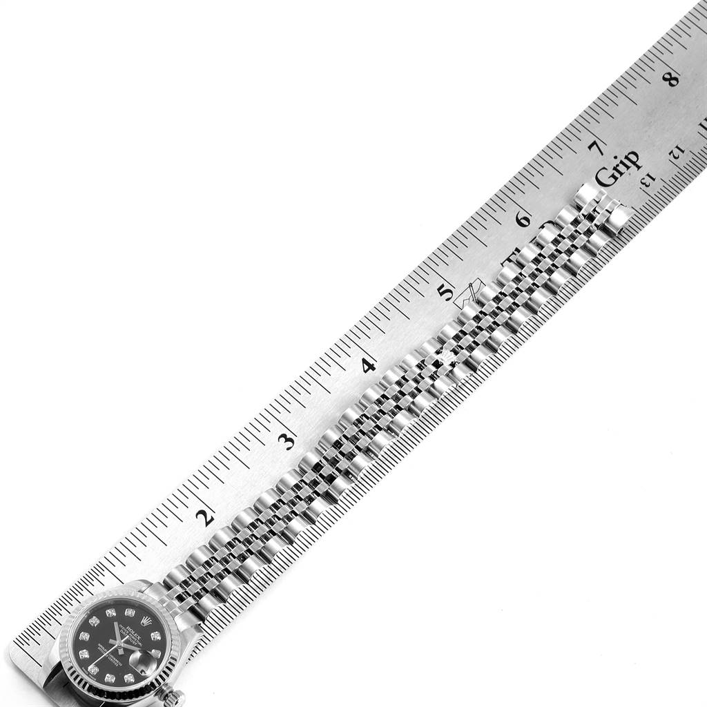 The image shows the Rolex Datejust 179174 Women
s Stainless Steel Black Dial 179174 Women
s Stainless Steel Black Dial watch face and stainless steel bracelet, positioned next to a ruler for measurement.