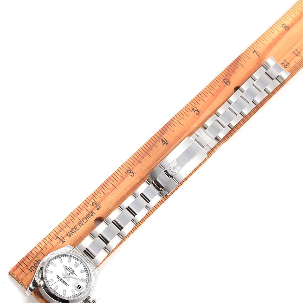 The Rolex Datejust 179160 Women's Stainless Steel White Dial 179160 Women's Stainless Steel White Dial watch is displayed flat with a wooden ruler alongside it, showing the case, dial, bracelet, and clasp.