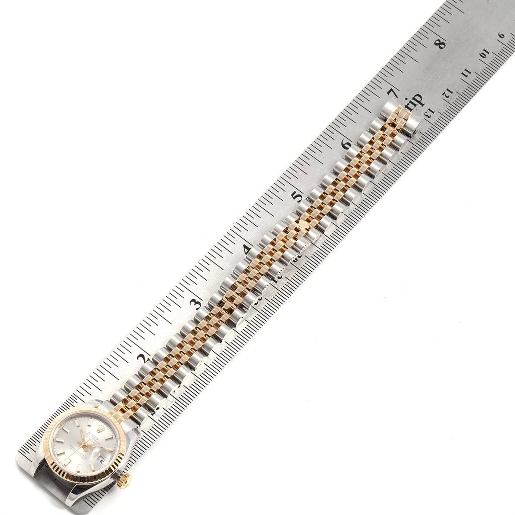 The image shows a Rolex Datejust 179173 Women's Steel and Gold (two tone) Silver Dial 179173 Women's Steel and Gold (two tone) Silver Dial watch laid flat next to a ruler, displaying its face, bezel, and bracelet.
