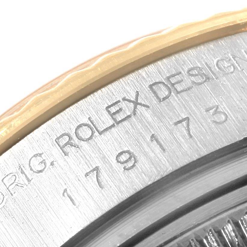 This close-up image of a Rolex Datejust 179173 Women's Steel and Gold (two tone) Silver Dial 179173 Women's Steel and Gold (two tone) Silver Dial shows the engraved serial number and fluted bezel.