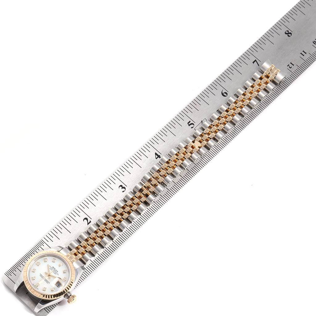 The image shows a Rolex Datejust 179173 Women's Steel and Gold (two tone) Mother of Pearl Dial 179173 Women's Steel and Gold (two tone) Mother of Pearl Dial watch laid flat, displaying its bracelet and dial alongside a ruler for scale.
