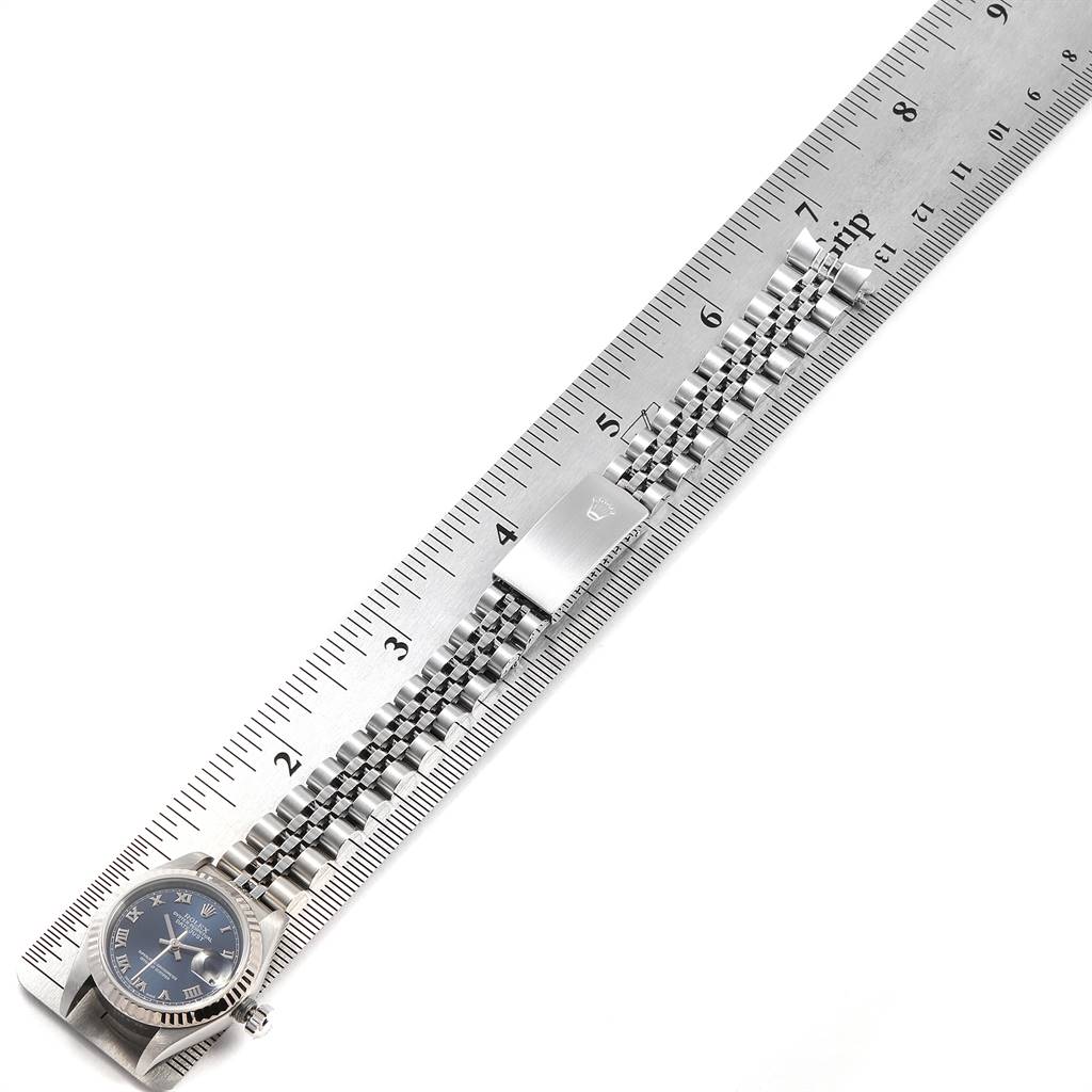 The Rolex Datejust 79174 Women's Stainless Steel Blue Dial 79174 Women's Stainless Steel Blue Dial watch is shown laid flat alongside a ruler, displaying its dial, bezel, and bracelet. 