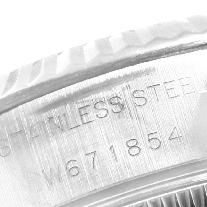 The image shows a close-up of the side of a Rolex Datejust 69174 Women's Stainless Steel White Dial 69174 Women's Stainless Steel White Dial, highlighting its fluted bezel and engraved serial number on the stainless steel.