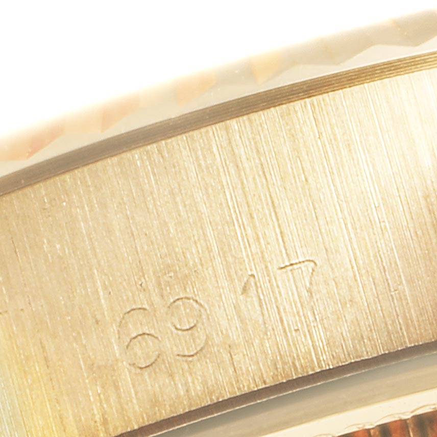 The image shows a close-up of the side of a Rolex Datejust 6917 Women
s Yellow Gold White Dial 6917 Women
s Yellow Gold White Dial watch, focusing on the engraving.