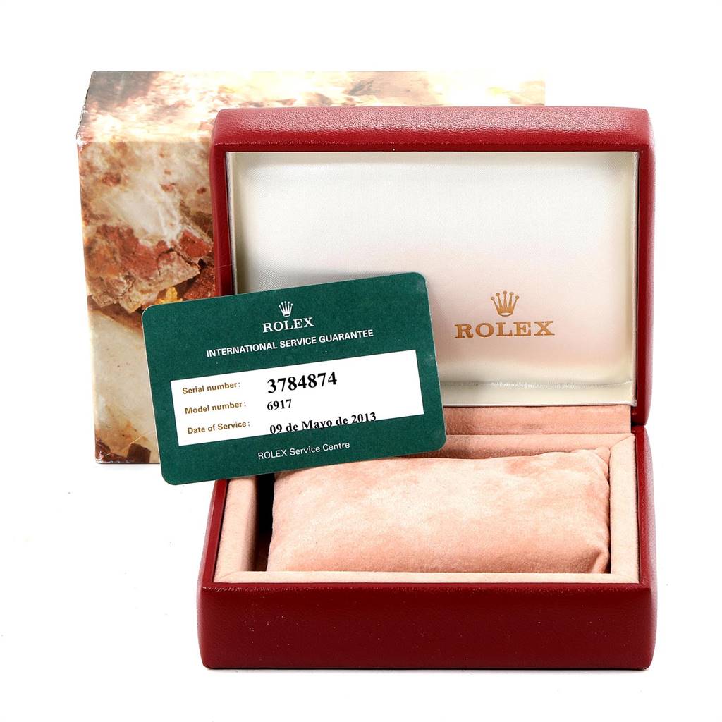 The image shows an open Rolex Datejust 6917 Women
s Yellow Gold White Dial 6917 Women
s Yellow Gold White Dial watch box with an international service guarantee card.