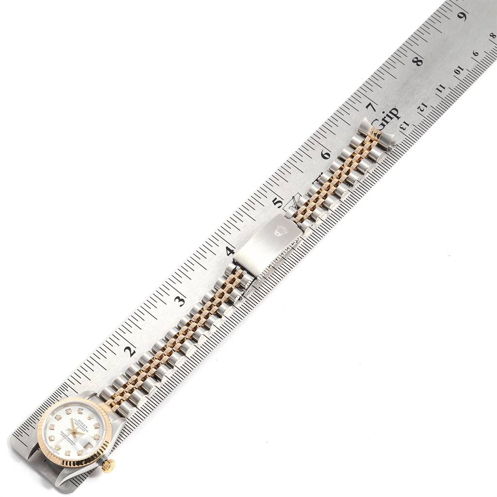 The image shows a top view of a Rolex Datejust 79173 Women's Stainless Steel White Dial 79173 Women's Stainless Steel White Dial watch, featuring its face, bezel, and part of its two-tone bracelet against a ruler.