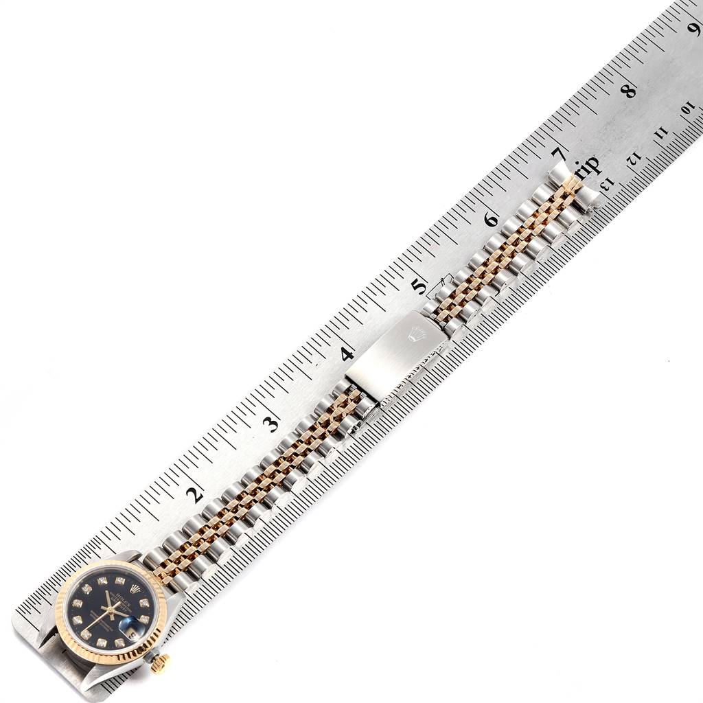 The image shows a Rolex Datejust 69173 Women's Stainless Steel Black Dial 69173 Women's Stainless Steel Black Dial watch laid parallel to a ruler, displaying the entire watch, including the dial, bracelet, and clasp.