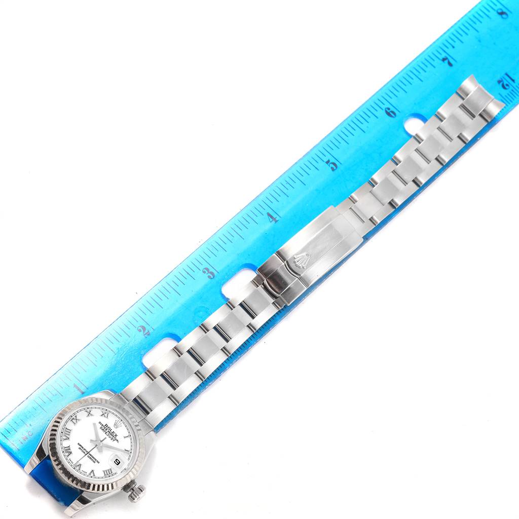 This image shows a Rolex Datejust 179174 Women's Stainless Steel White Dial 179174 Women's Stainless Steel White Dial watch in a flat lay position, highlighting the watch face, bracelet, and clasp alongside a ruler.