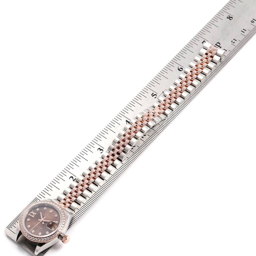 The Rolex Datejust 279171 Women's Steel and Gold (two tone) Brown Dial 279171 Women's Steel and Gold (two tone) Brown Dial watch is shown from a top view, highlighting its face, bezel, and bracelet, alongside a ruler.