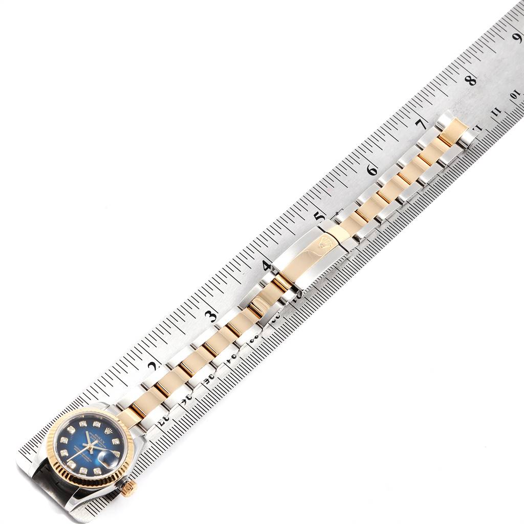 The Rolex Datejust 179173 Women's Steel and Gold (two tone) Blue Dial 179173 Women's Steel and Gold (two tone) Blue Dial watch is shown from an overhead angle with the face and bracelet visible, aligned next to a ruler.