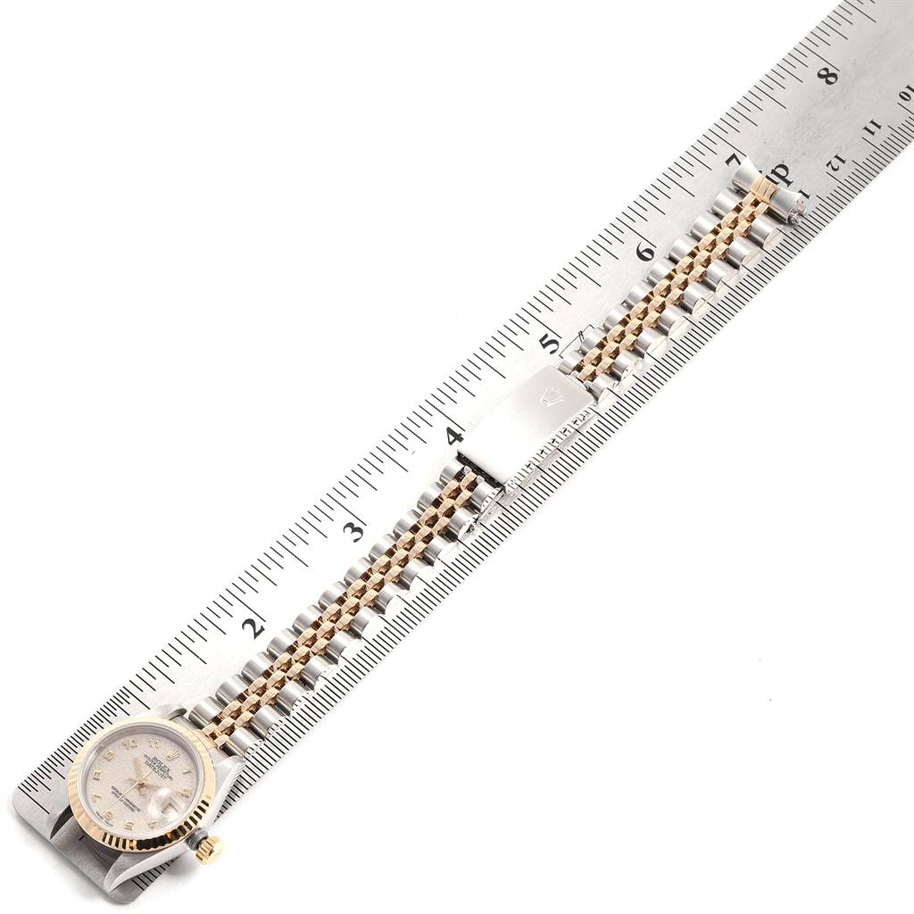 This image shows the Rolex Datejust 69173 Women's Stainless Steel Beige Dial 69173 Women's Stainless Steel Beige Dial watch laid parallel to a measuring ruler, displaying its face, bracelet, and clasp.