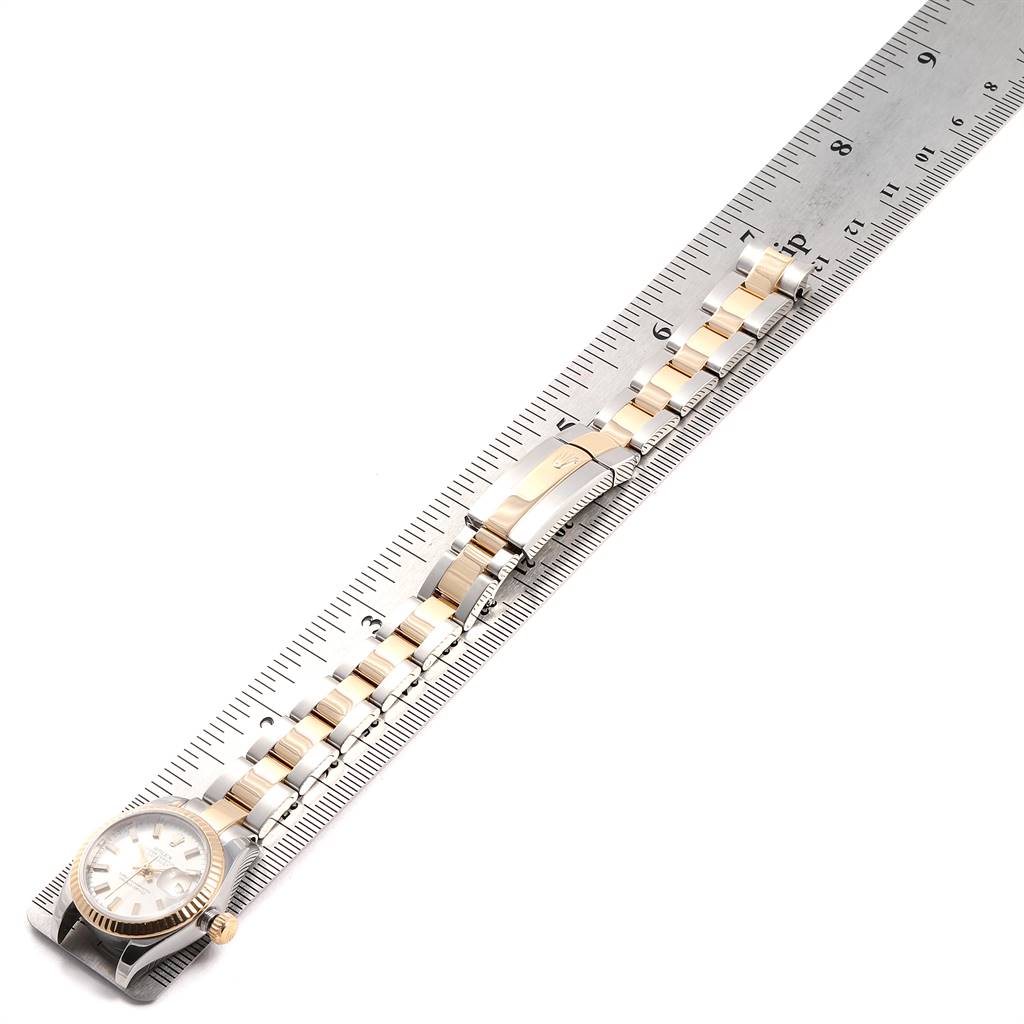 The Rolex Datejust 179173 Women's Steel and Gold (two tone) Silver Dial 179173 Women's Steel and Gold (two tone) Silver Dial watch is shown from an overhead angle, displaying its face, bracelet, and measurement against a ruler.